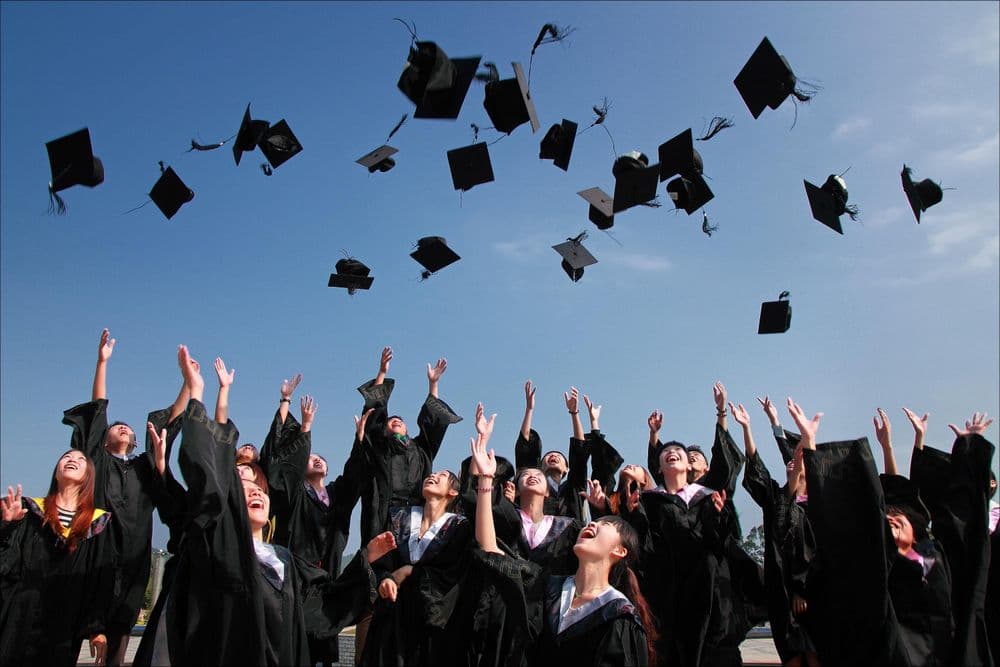 Graduates tossing caps into a clear sky